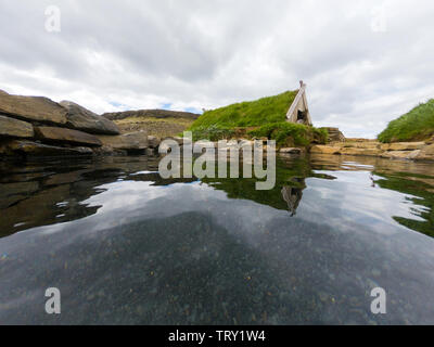 Weitwinkelaufnahme eines Torfhaus und einem geothermischen Hot Spring Pool in Hrunalaug, Island Stockfoto