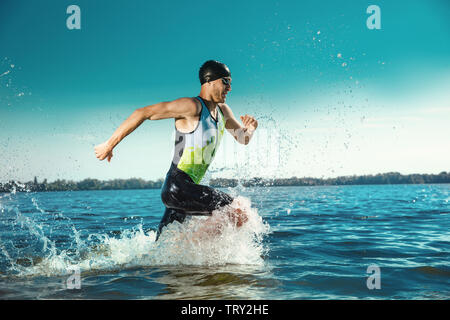 Professioneller Triathlet schwimmen in River's offene Wasser. Mann, Schwimmen Ausrüstung üben Triathlon auf dem Strand, in der Sommertag. Konzept der gesunden Lebensstil, Sport, Action, Bewegung und Bewegung. Stockfoto