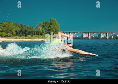 Professioneller Triathlet schwimmen in River's offene Wasser. Mann, Schwimmen Ausrüstung üben Triathlon auf dem Strand, in der Sommertag. Konzept der gesunden Lebensstil, Sport, Action, Bewegung und Bewegung. Stockfoto