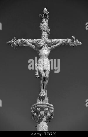 Schwarzweiß-Bild von einem Stein Statue von Christus am Kreuz auf einem Friedhof in La Feuillée, Bretagne, Frankreich. Stockfoto