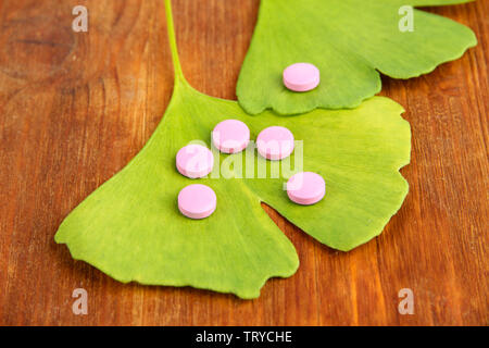 Ginkgo Biloba Blätter und Pillen auf Holz- Hintergrund Stockfoto