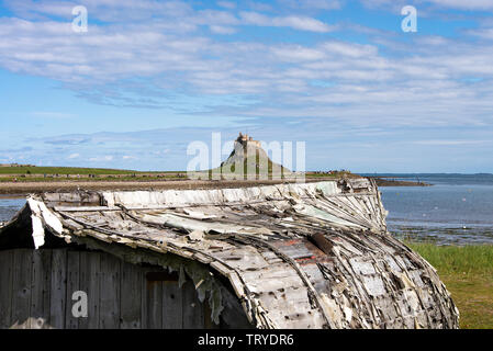 Alte umgedrehte Fishing Boat Rümpfe als Hütte mit Lindisfarne Castle auf Holy Island Northumberland England Vereinigtes Königreich Großbritannien Stockfoto