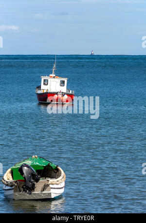 Fischerboote vor Holy Island in einer geschützten Bucht mit Longstone Lighthouse im Hintergrund vertäut Northumberland England Vereinigtes Königreich Großbritannien Stockfoto