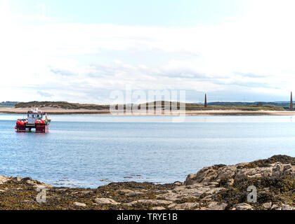 Fischerboot vor Holy Island in einer geschützten Bucht mit Hafeneinfahrt Pylons im Hintergrund Northumberland England Vereinigtes Königreich Großbritannien Stockfoto