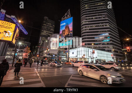 TORONTO, ONTARIO - November 13, 2018: Wolkenkratzer auf der Yonge Dundas Square, mit Menschen überfahrt auf einem Bürgersteig in der Nacht, Geschäfte und Läden, in einem typischen Stockfoto