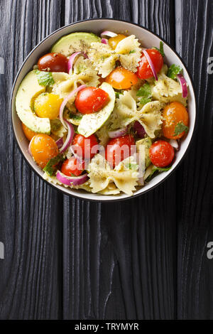 Pasta Farfalle mit reife Avocado, Zwiebeln und Tomaten close-up in einer Schüssel auf den Tisch. Vertikal oben Ansicht von oben Stockfoto