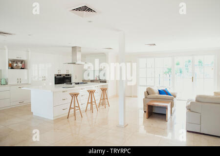 Weitwinkelaufnahme eines leeren Küche Interieur. Die Küche ist mit einem Frühstück Insel in der Nähe des Herdes und es ist geplant, in der Lage, in die Liv zu sehen Stockfoto