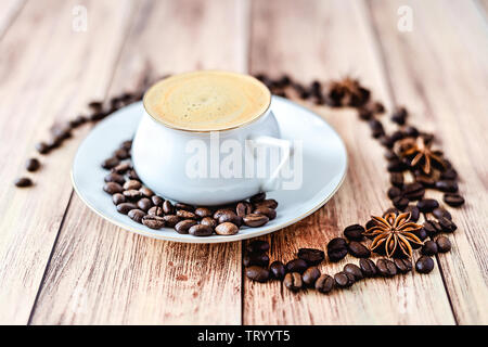 Nahaufnahme einer Tasse heißen Kaffee auf Holz- rustikalen Tisch mit verschüttete Kaffeebohnen und Anis. Platz für Text. Stockfoto