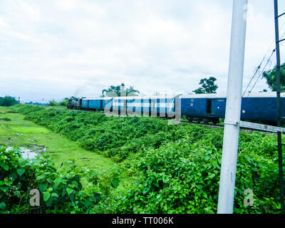 Anzeigen von Kolkata zu Jaldapara, den Zug in der Nähe von Türen Jaldapara Bereich Reisen auf Schienen durch die grünen, grünen Wiesen mit robusten Pilatus im Hinterg Stockfoto