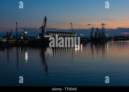 Burrgas Hafen bei Nacht. Silhouetten von Kränen und Spiegelungen im Wasser. Stockfoto