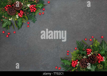 Weihnachten Hintergrund Grenze mit Winter Flora von Holly und lockere Beeren, Mistel, Efeu und Zeder Blätter auf grunge grauer Hintergrund mit kopieren. Stockfoto