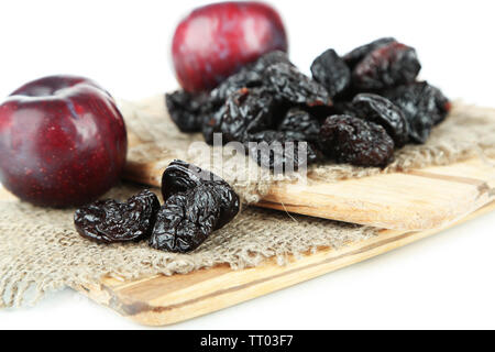 Frische und getrocknete Pflaumen auf Holzbrett, isoliert auf weißem Stockfoto