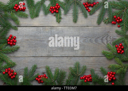 Weihnachtskarte mit Tannenbaum, Zweige und roten Vogelbeeren auf Holzuntergrund - text Raum Stockfoto