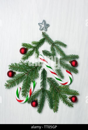 Weihnachtsbaum Konzept mit grünen Tannenbaum Äste, rote Kugeln und Zuckerstangen auf weißem Hintergrund Stockfoto