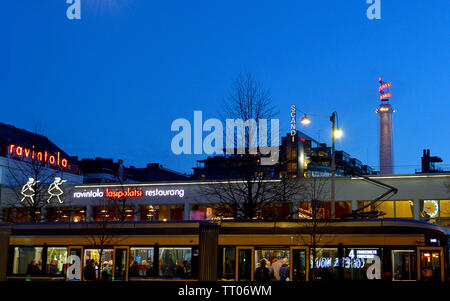 HELSINKI, Finnland - 6 April 2019: ein Tram Car übergibt die Neonbeleuchteten Ravintola Restaurant im lasipalatsi Komplex, jetzt einschließlich Amos Rex Art Gallery. Stockfoto