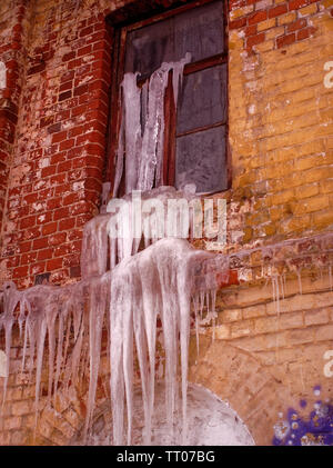 Große Eiszapfen hängen von einem alten Backsteinhaus, Russland Stockfoto