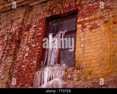 Große Eiszapfen hängen von einem alten Backsteinhaus, Russland Stockfoto