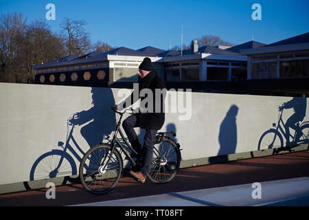 Mann auf einem Fahrrad in die Innenstadt von Amsterdam im Winter Sonnenschein Stockfoto