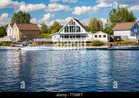 Ein wasser Skifahrer Fahrten hinter den Luxus Ferienwohnungen rund um Spring Lake in der Cotswold Water Park, Cirencester, Gloucestershire. Stockfoto