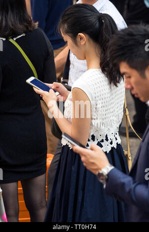 Fußgänger, die sich auf Mobiltelefone in der Straße, Hong Kong, SAR, China Stockfoto