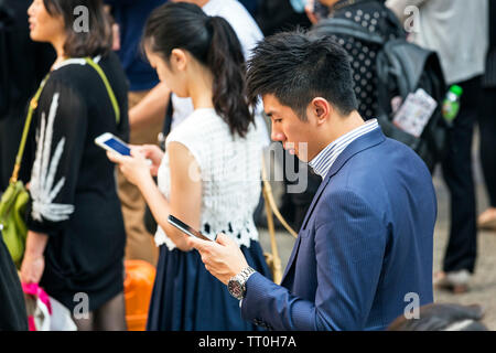 Fußgänger, die sich auf Mobiltelefone in der Straße, Hong Kong, SAR, China Stockfoto