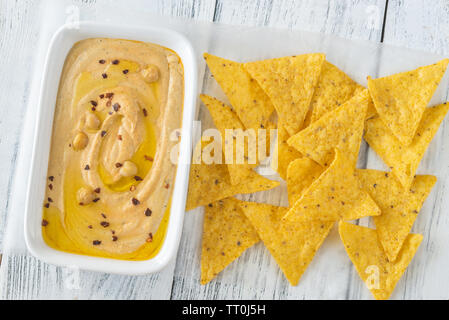 Schüssel mit Hummus mit Tortilla Chips auf dem hölzernen Tisch Stockfoto