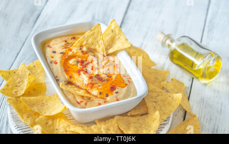 Schüssel mit Hummus mit Tortilla Chips auf dem hölzernen Tisch Stockfoto