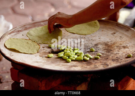 Eine Mexikanerin kochen Tortillas auf einer mexikanischen drei Stein Herd durch Holz- und Bohnen, ländliche Szene gefeuert Stockfoto