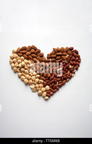 Herzförmige Komposition mit Mandeln, Haselnüsse und Erdnüsse auf weißem Hintergrund Stockfoto
