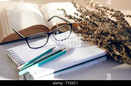 Cute locker Stillleben mit Blumen von Wermut, der im Bouquet ordentlich neben Büchern, Brillen und Schreibgeräte Stockfoto
