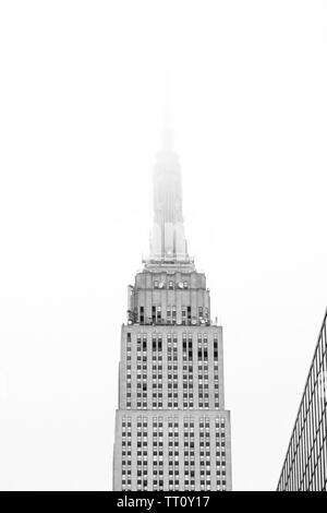 New York City - 13. Mai 2018: die obere Hälfte des Empire State Building mit Turm im Nebel verloren. Schwarz und Weiß. Stockfoto