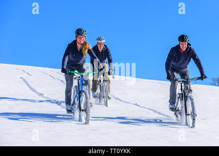 Drei Radfahrer während abwärts im tiefen Neuschnee im winterlichen Allgäu Stockfoto