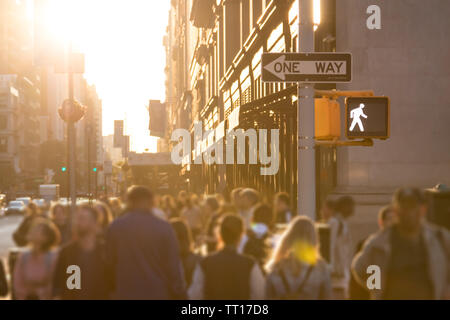 Sonnenlicht scheint auf den geschäftigen Menschenmassen von anonymen Personen auf der Straße in Manhattan, New York City NYC Stockfoto