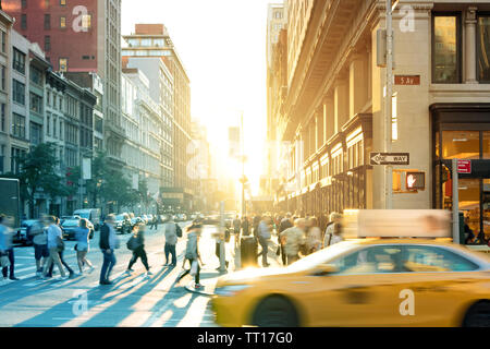 New York City yellow Taxi cab Geschwindigkeiten Vergangenheit die Menschenmassen an der Kreuzung der 23. Straße und 5th Avenue in Midtown Manhattan NYC Stockfoto