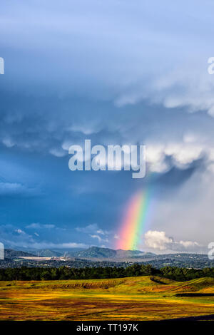 Dramatische Gewitterwolken und ein Regenbogen über dem Oroville Dam und den Ausläufern im Hintergrund. Stockfoto