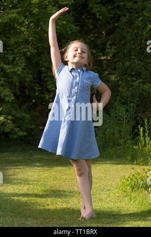 Acht Jahre alten Mädchen tanzen in der Schule uniform Kleid nach der Schule im Garten für die Kamera posieren, voller Vertrauen Stockfoto