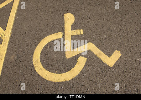 Nahaufnahme der behinderten Parkplatz Symbol in gelben Fahrbahnmarkierungen im Auto Park, Edinburgh, Schottland Stockfoto