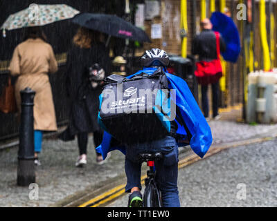 Eine Stuart Firma Food Delivery Kurier Fahrten durch Londoner Regen. Stuart konkurriert mit Deliveroo und Uber isst in diesem hart umkämpften Markt Stockfoto