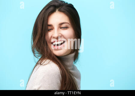 Portrait einer jungen kaukasischen Frau mit langem Haar, glücklich und lächelnd, auf blauem Hintergrund isoliert Stockfoto