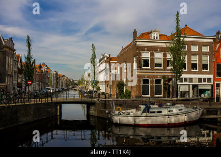 Gouda, Holland, Niederlande, April 23, 2019, Fahrräder und in der Nähe einer Brücke entlang einer Straße geparkt, Canal in Gouda Altstadt. Blumen in einem blumenbeete, Boot Stockfoto