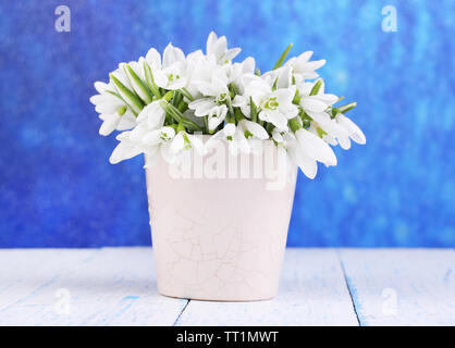 Schönen Schneeglöckchen in Vase, auf Holztisch auf hellen Hintergrund Stockfoto