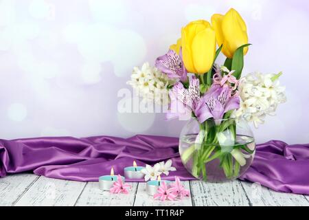 Blumen in der Vase mit Kerzen auf dem Tisch auf hellen Hintergrund Stockfoto