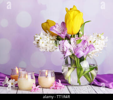 Blumen in der Vase mit Kerzen auf dem Tisch auf hellen Hintergrund Stockfoto