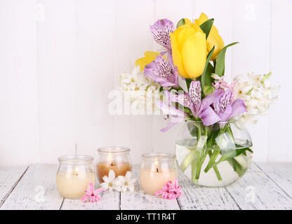 Blumen in der Vase mit Kerzen auf dem Tisch auf hölzernen Hintergrund Stockfoto