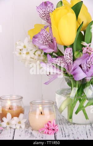 Blumen in der Vase mit Kerzen auf dem Tisch auf hölzernen Hintergrund Stockfoto