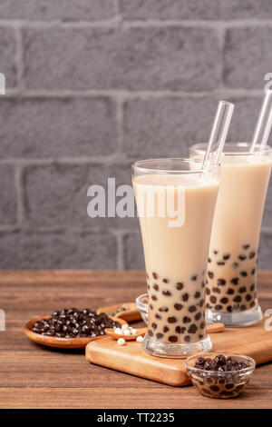 Beliebte Taiwan Getränk - Bubble Milch Tee mit Tapioka Perlen Kugel in Glas und Stroh, Holz- Tabelle grau Ziegelstein Hintergrund, Nahaufnahme, kopieren Raum Stockfoto