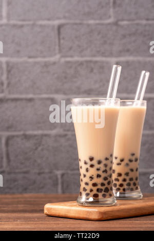Beliebte Taiwan Getränk - Bubble Milch Tee mit Tapioka Perlen Kugel in Glas und Stroh, Holz- Tabelle grau Ziegelstein Hintergrund, Nahaufnahme, kopieren Raum Stockfoto