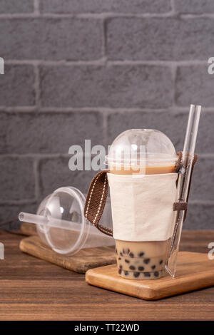 Takeout mit Einweg los Konzept beliebt Taiwan bubble Milch trinken Tee mit Schale aus Kunststoff und Stroh auf Holztisch, Hintergrund, Nahaufnahme, kopieren Raum Stockfoto