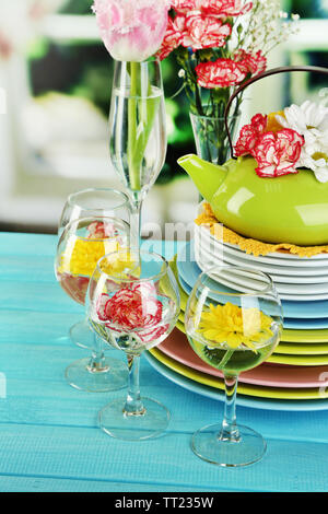 Stapel bunter Keramik Geschirr und Blumen, auf Holztisch, auf hellen Hintergrund Stockfoto