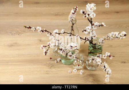 Schöne Aprikosen blühen in transparenten Gläser auf Holz- Hintergrund Stockfoto